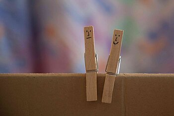 Symbolbild Hilfe bei psychischer Erkrankung. Zwei Holz-Wäscheklammern mit aufgezeichneten Gesichtern.