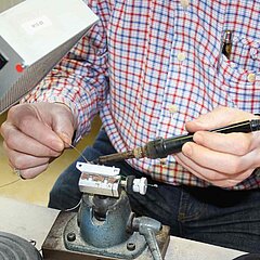 Bild von einer Person, die an einem Elektroteil lötet.