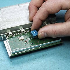 Bild von der Hand einer Person, die ein Bauteil auf eine Platine steckt.