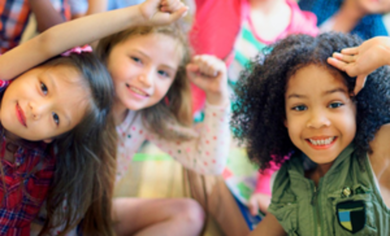 Drei Kinder schauen aufmerksam bis fröhlich in die Kamera.