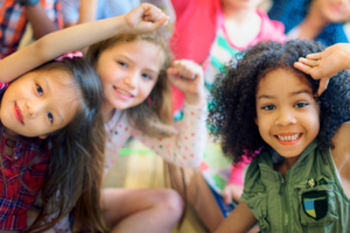 Drei Kinder schauen aufmerksam bis fröhlich in die Kamera.