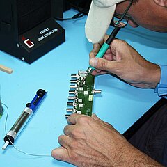 Bild von einer Person, die an elektronischen Teilen lötet.