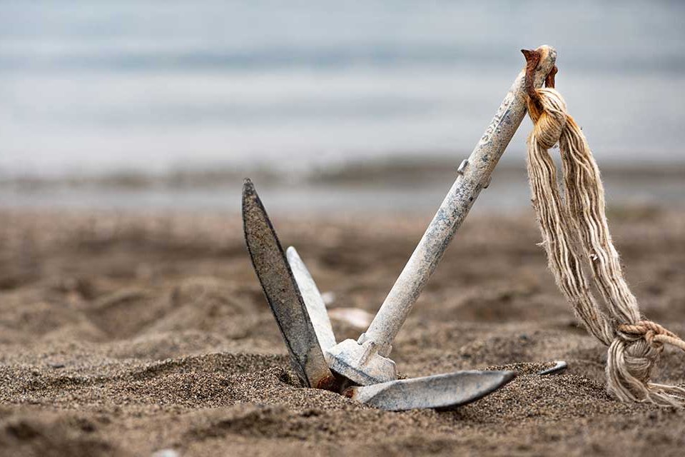 Symbolbild. Ein Anker, der im Sand am Strand liegt. Symbolbild. Ein Anker, der im Sand am Strand liegt.