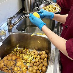 Bild von vier Händen beim Kartoffelschälen in der Produktionsküche des AKTIV Werk Wetterau.